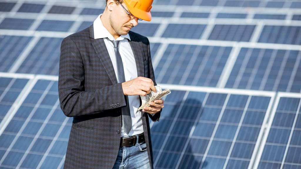 person counting money with solar panels in the background