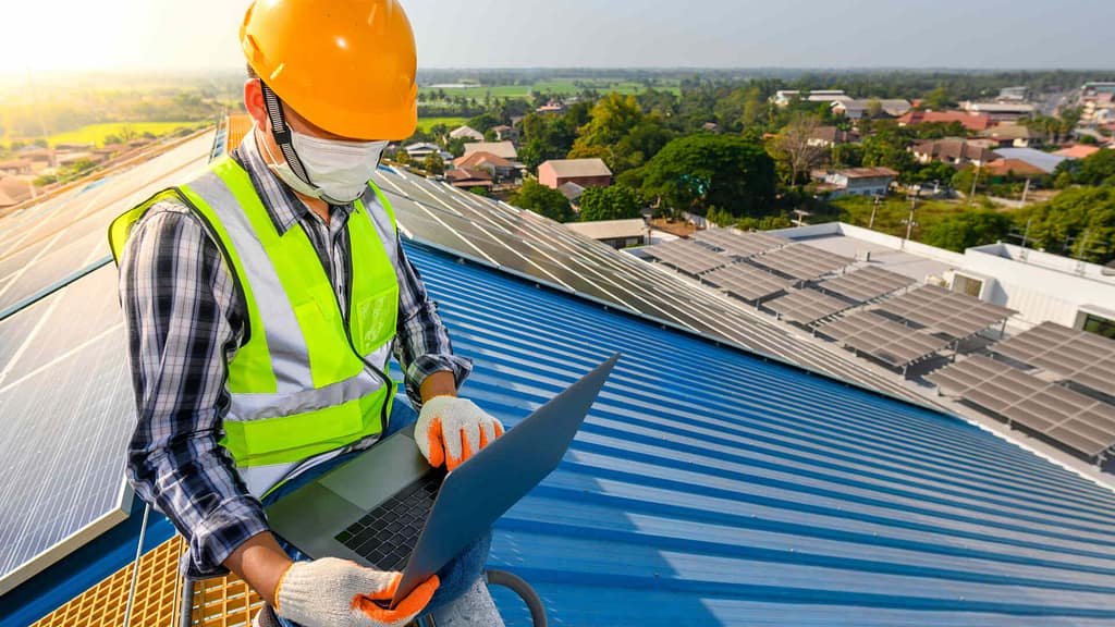 technician with laptop examining solar panels on Maui