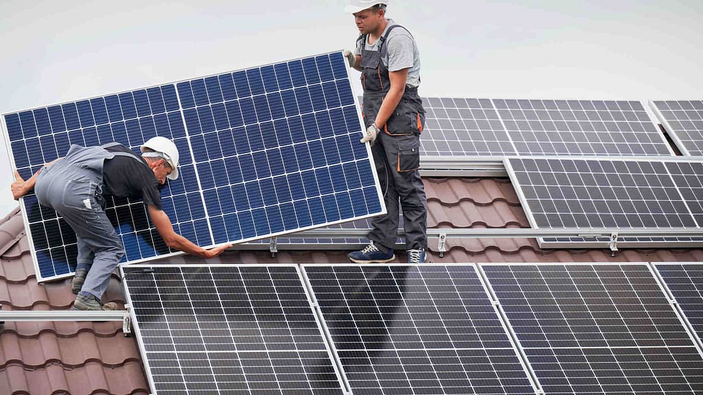 two professional installing solar panels on top of the roof