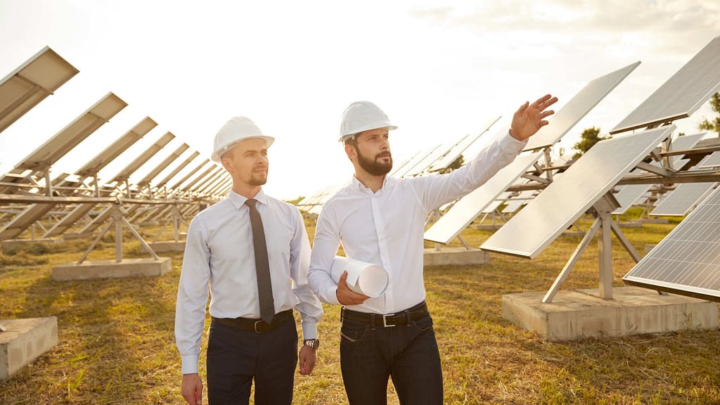 two men wearing white hard hat checking the solar panel site